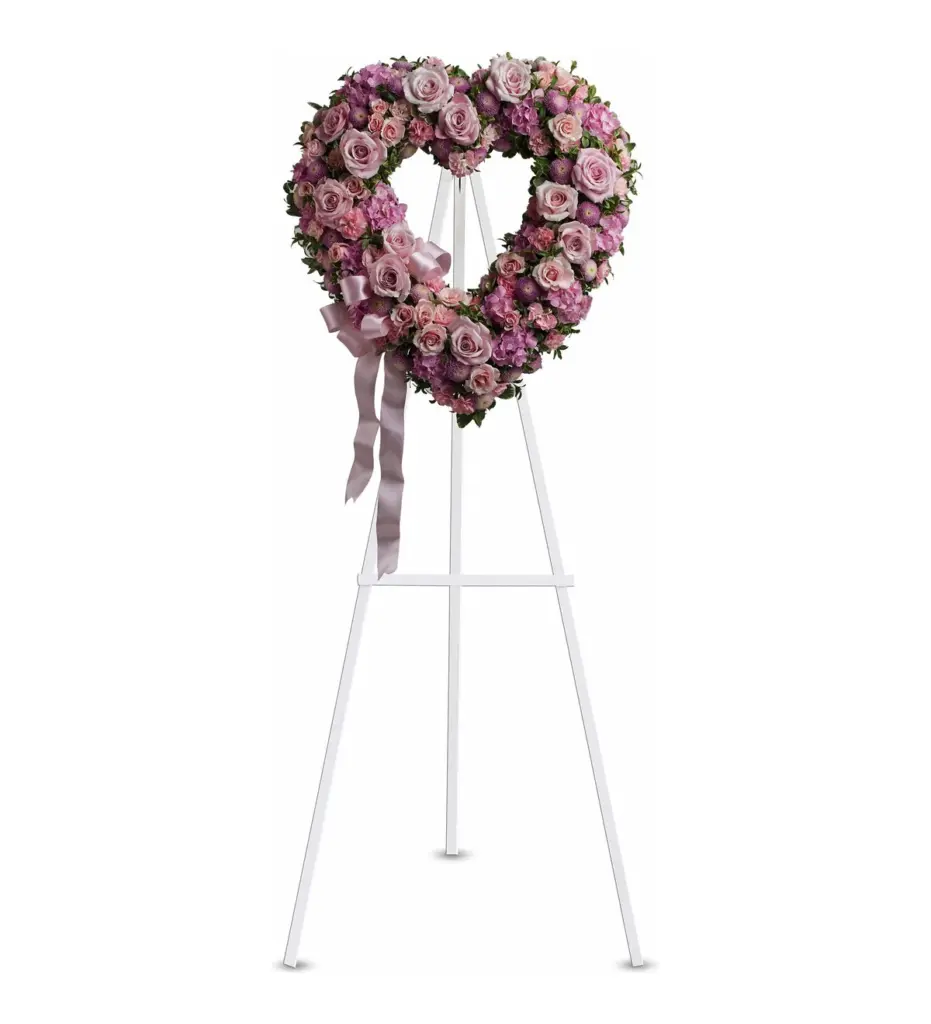 Pink open heart of roses and hydrangea with a satin bow on a white easel