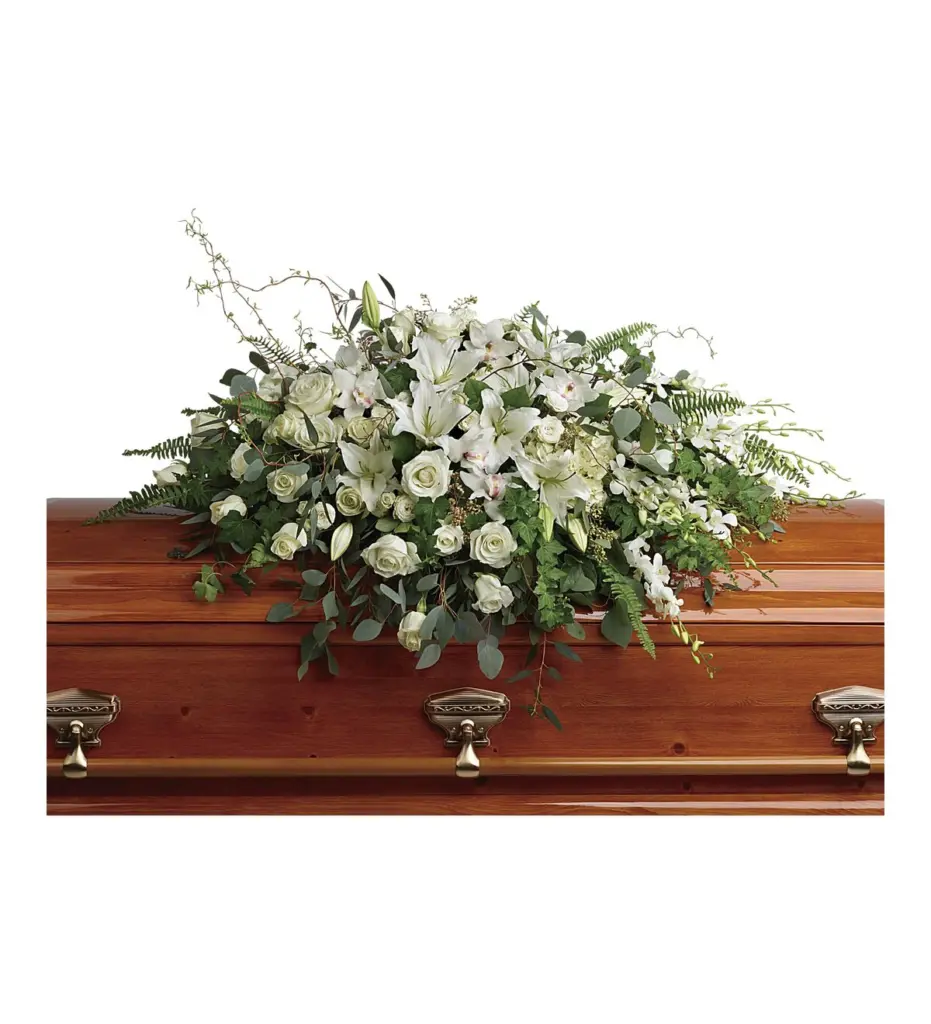 White roses, lilies and orchids casket spray on a polished wooden casket