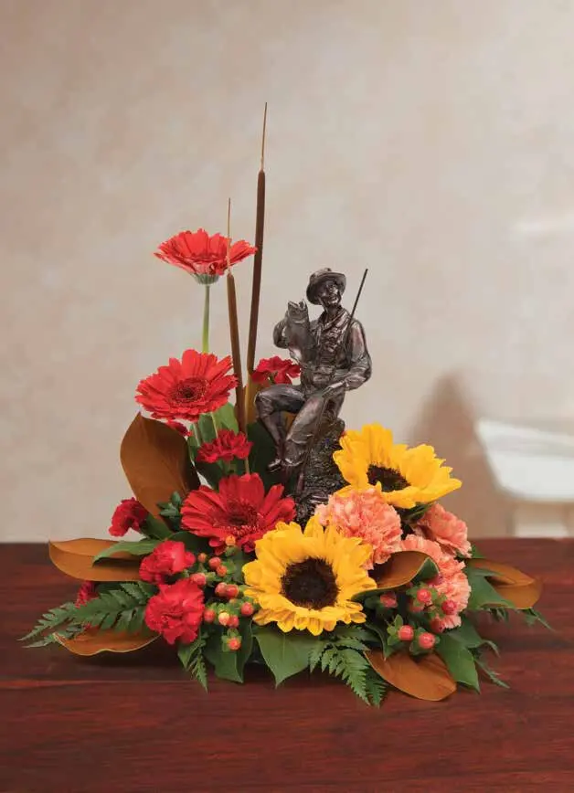 Fisherman figurine surrounded by sunflowers, red gerberas and cattails