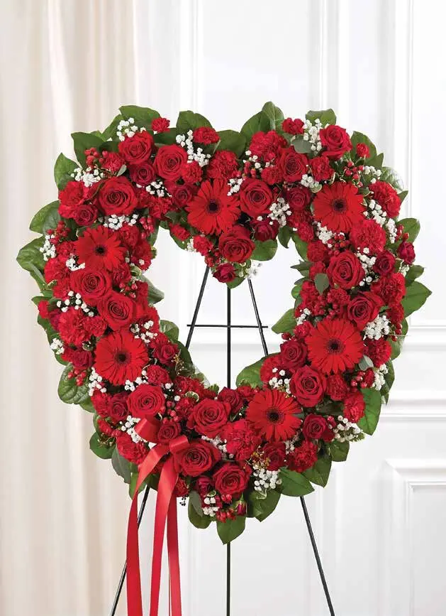Open red heart of roses, gerberas and carnations on an easel with red ribbon