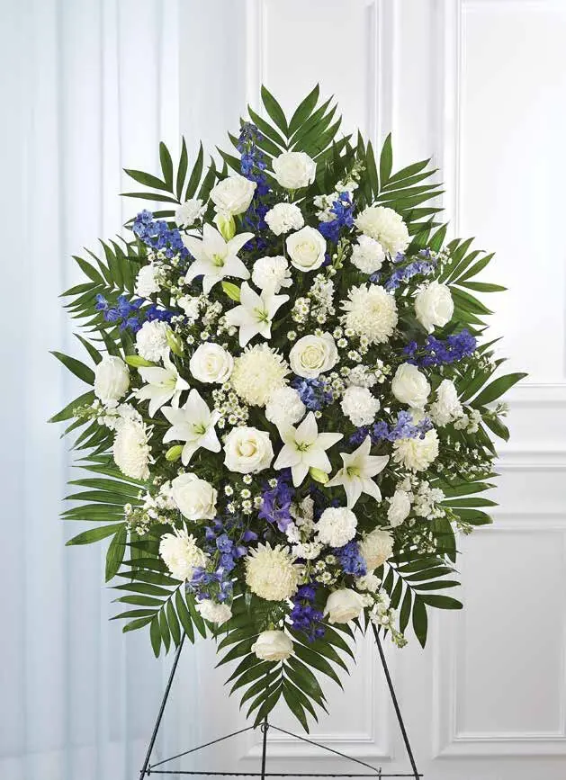 Blue and white standing spray of roses, lilies and delphinium on an easel