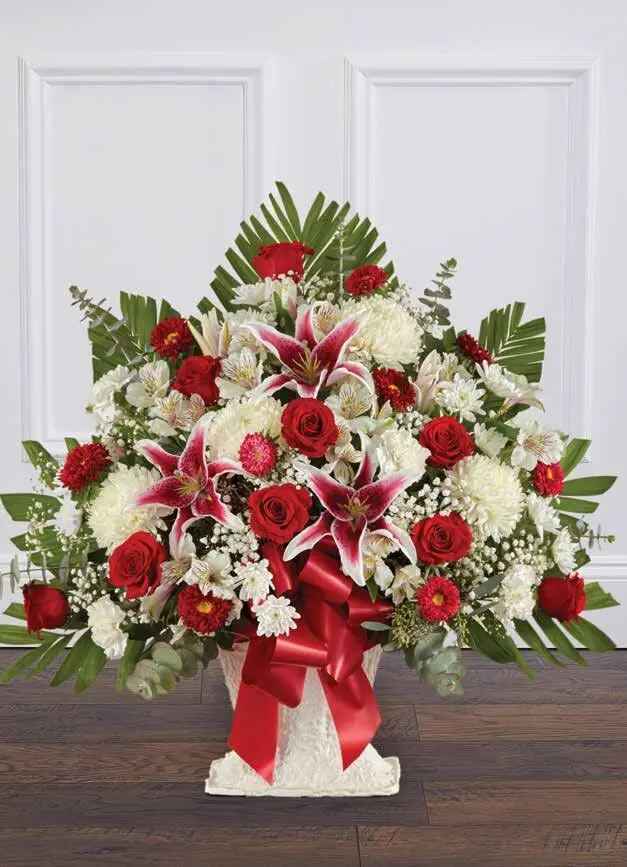 Red roses, pink lilies and white mums in a white floor basket with red bow