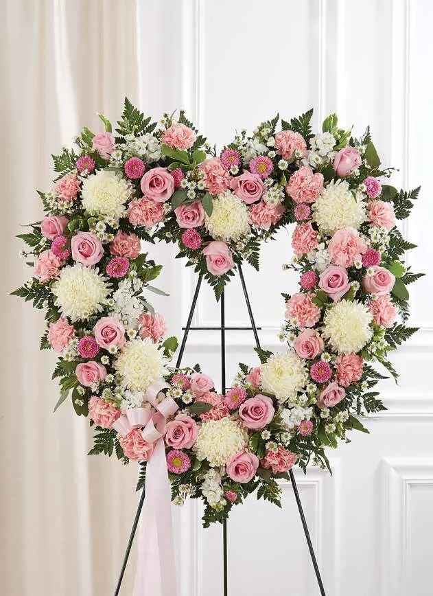 Open pink and white heart of roses and carnations with a pink bow