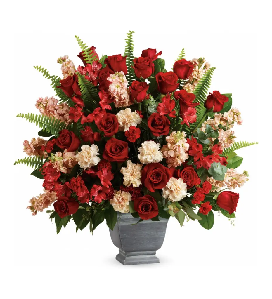 Large arrangement of red roses and peach stock in a gray footed container
