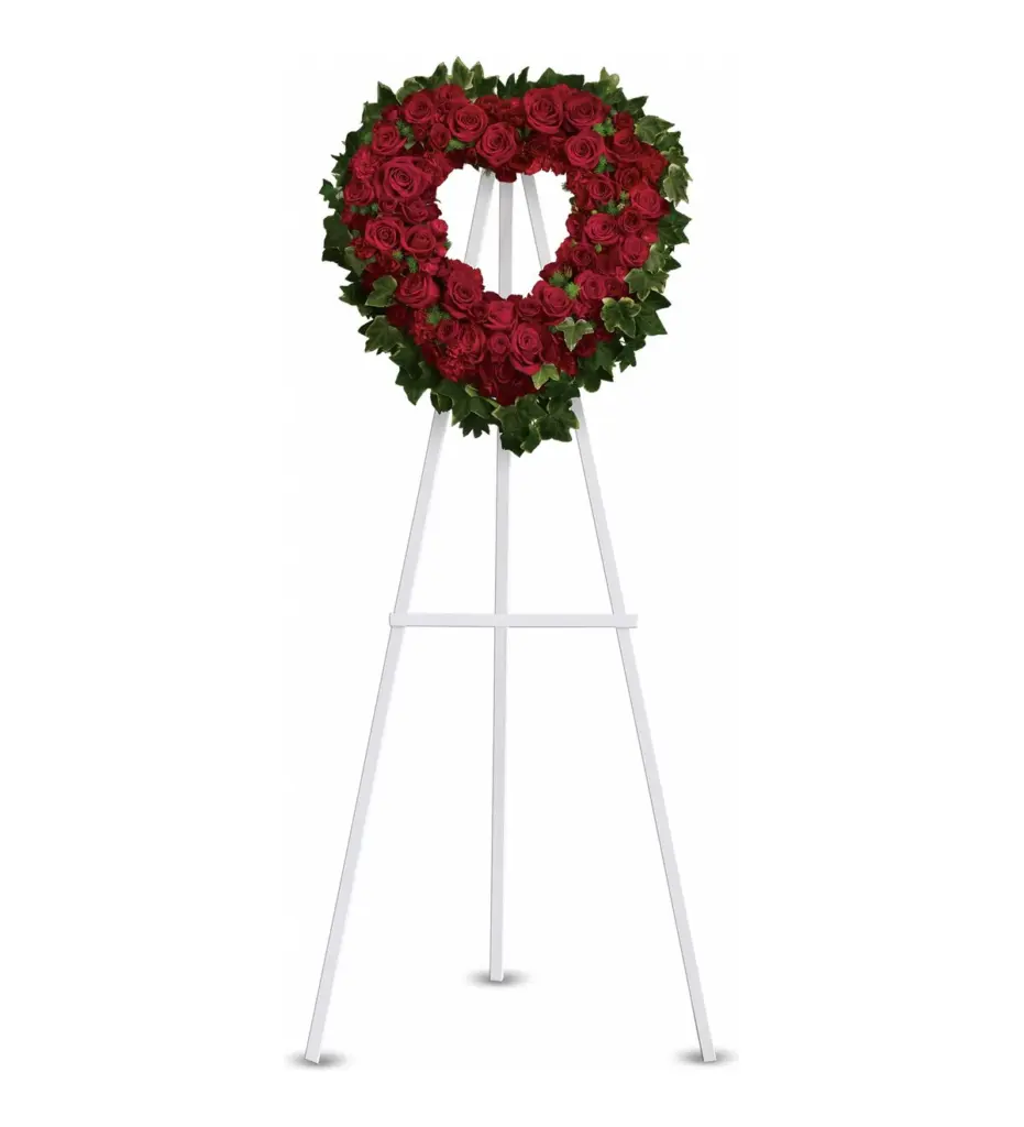 Open heart of red roses and carnations framed by ivy on a white easel