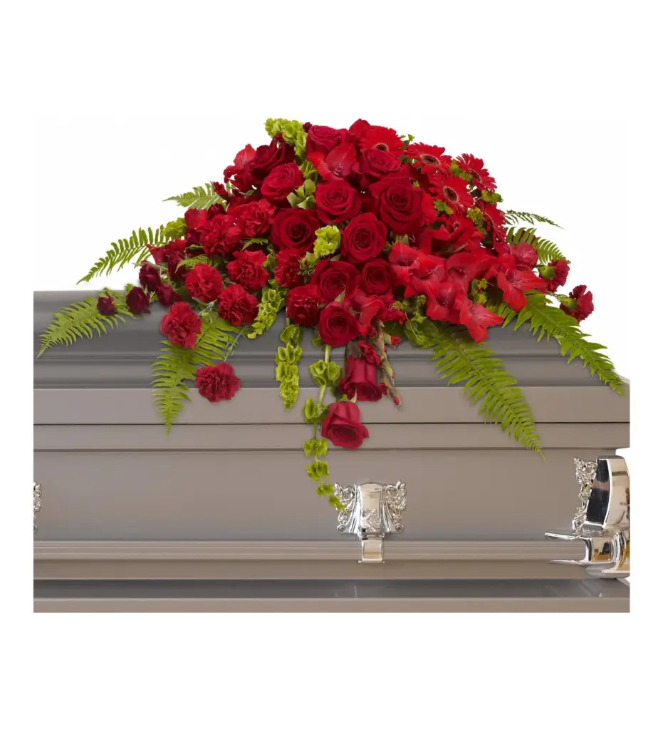 Red rose and gerbera half casket spray on a gray casket lid