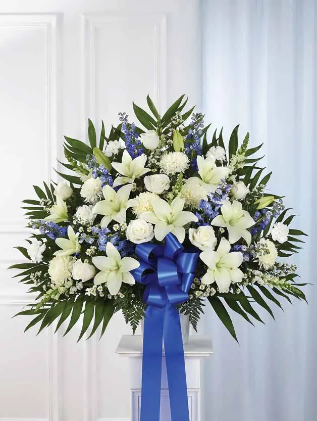 Blue and white basket of lilies, roses and delphinium on a white pedestal