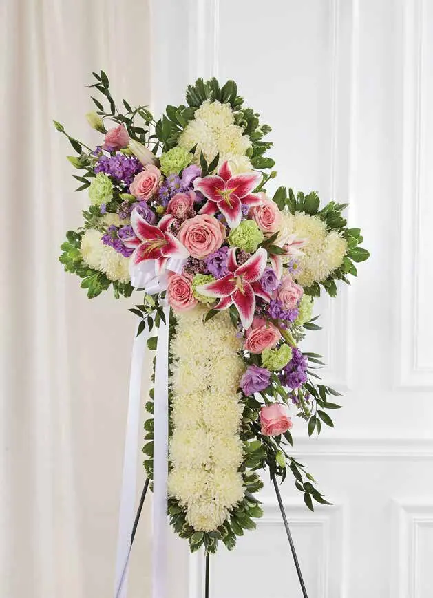 White chrysanthemum cross with pink lilies and roses on an easel with ribbon