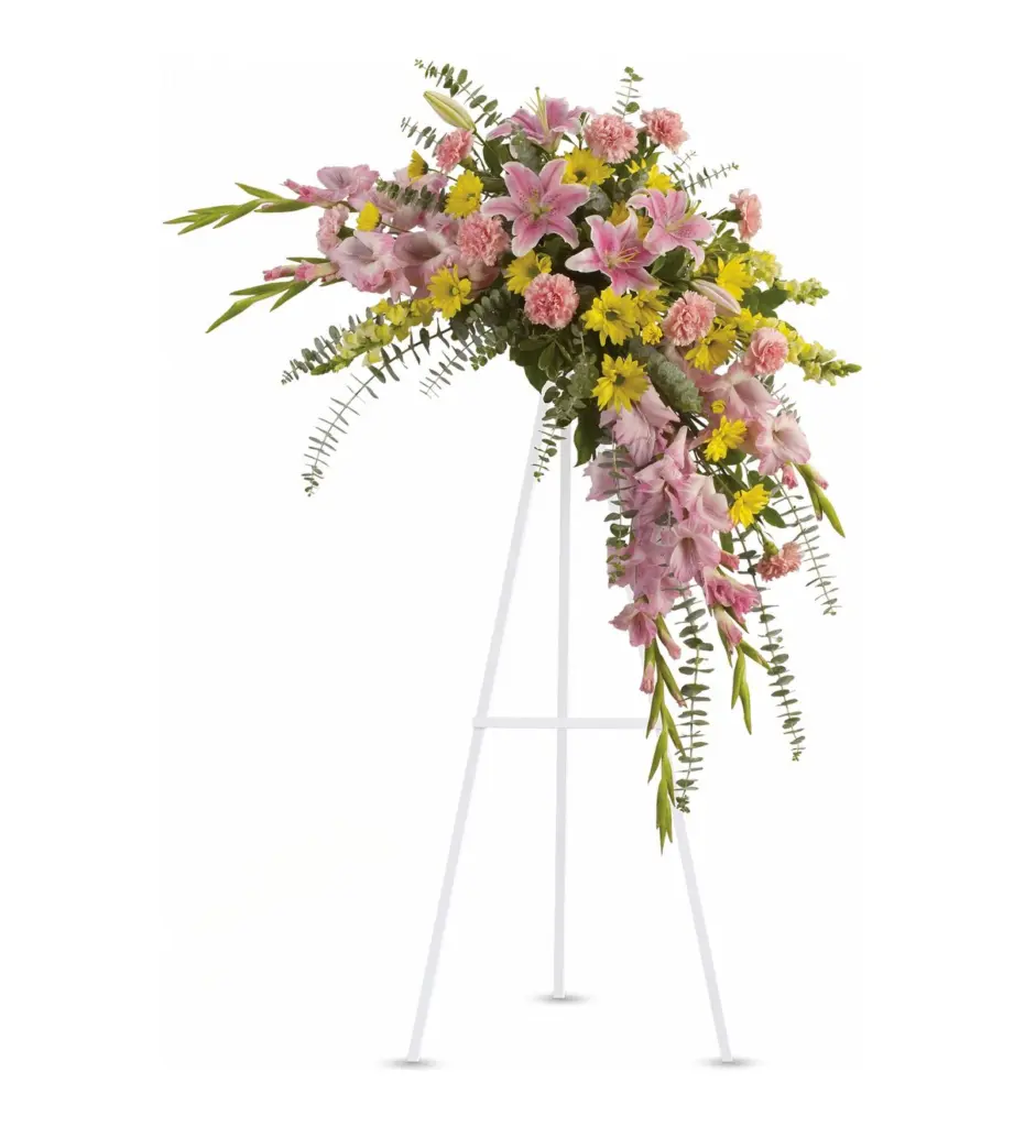 Crescent standing spray of pink lilies, gladiolus and yellow daisies on white easel