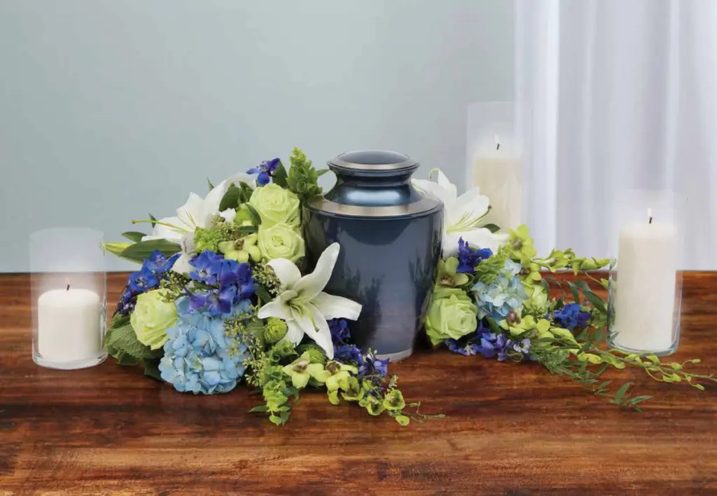 Blue urn surrounded by white lilies, green roses and blue hydrangea with candles