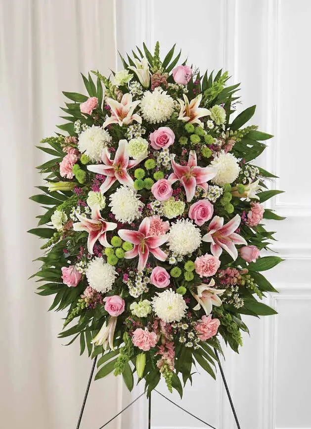 Pastel pink and white oval standing spray of lilies and roses on an easel