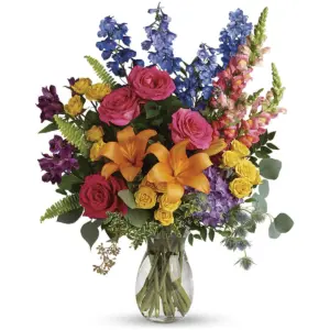 Hot pink roses, orange lilies and blue delphinium in a clear glass vase