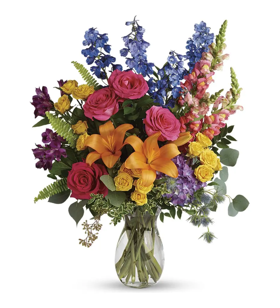 Tall vase of pink roses, orange lilies, blue delphinium and yellow spray roses