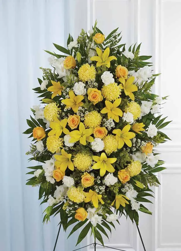 Oval yellow and white standing spray of lilies, roses and mums on an easel
