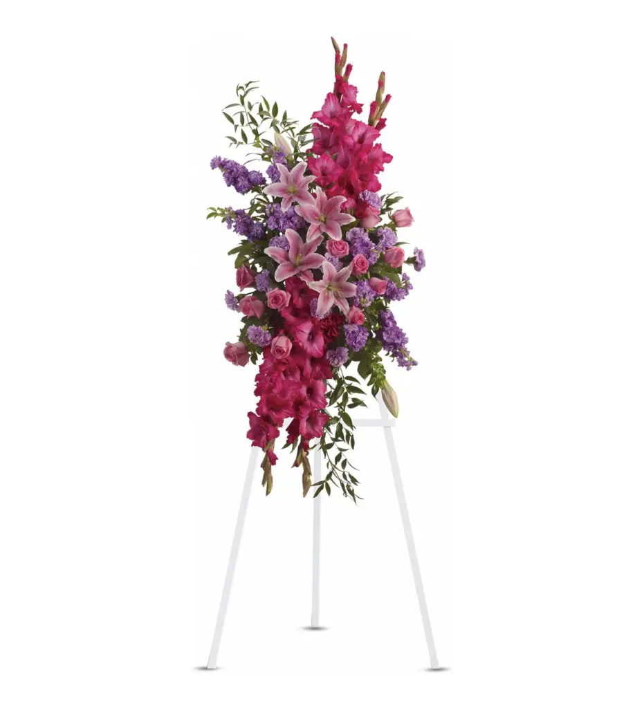Pink gladiolus, lilies and roses standing spray on a white easel
