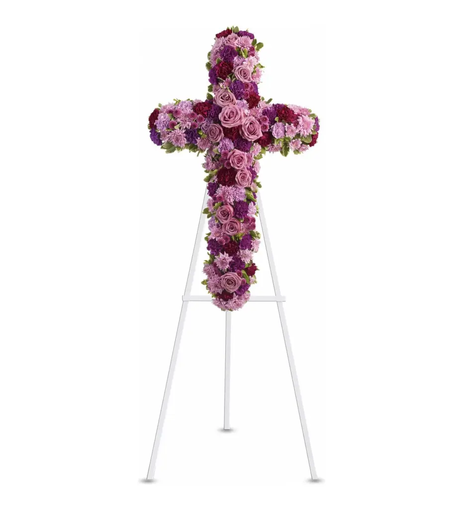 Lavender and pink floral cross of roses and carnations on a white easel