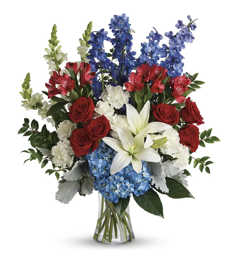 Red roses, white lilies and blue delphinium in a clear glass vase