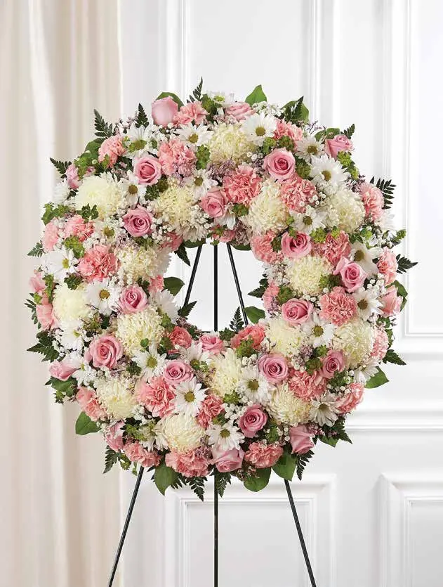 Pink and white standing wreath of roses, carnations and mums on an easel