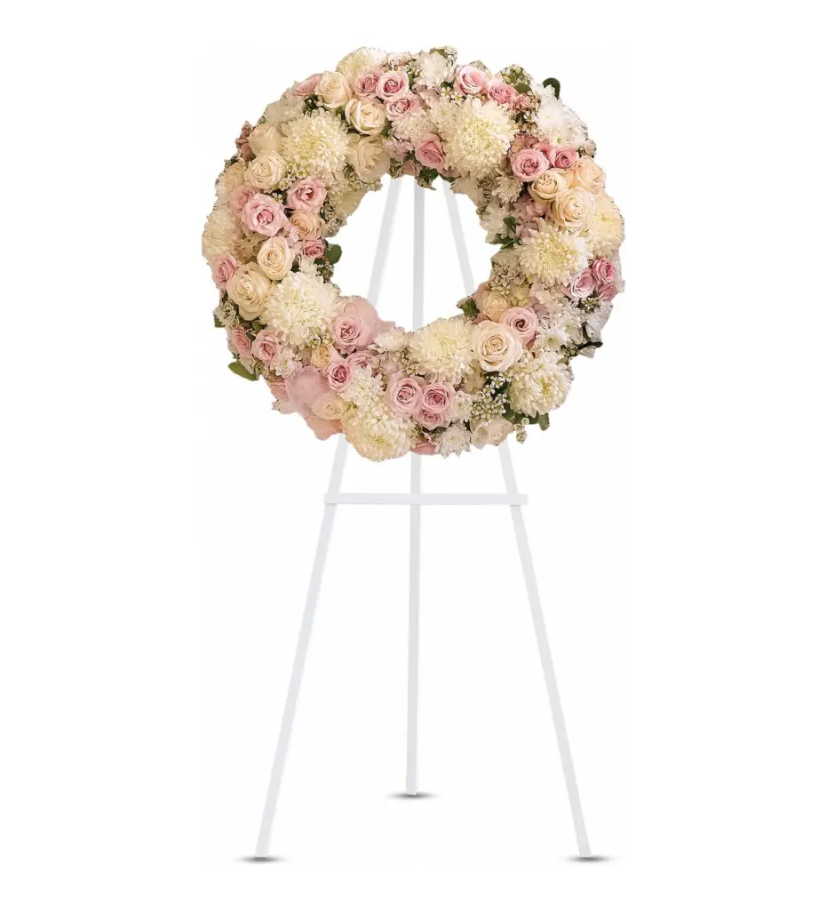 Standing wreath of pink roses and peach blooms on a white easel