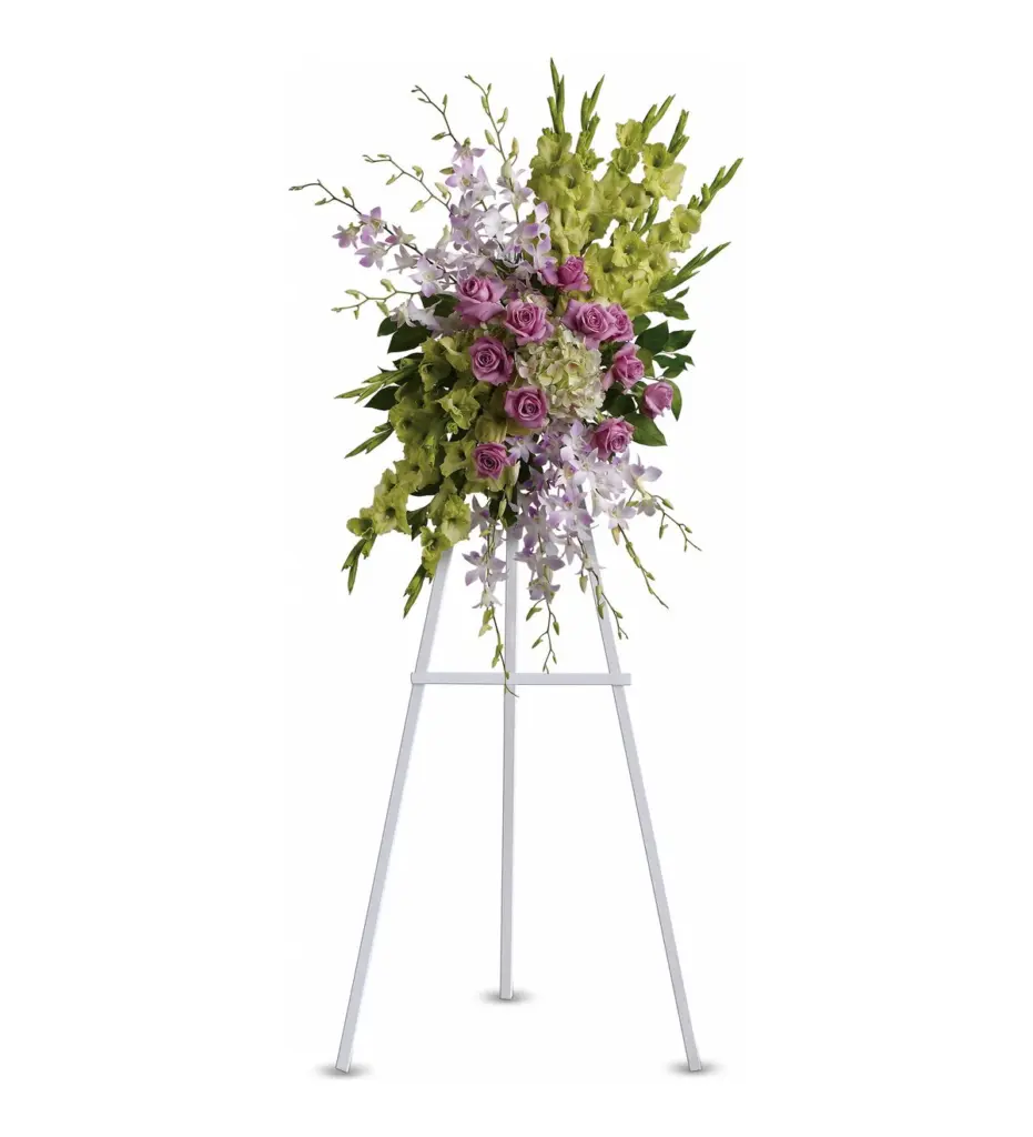 Lavender roses and orchids with green gladiolus in a standing spray on white easel