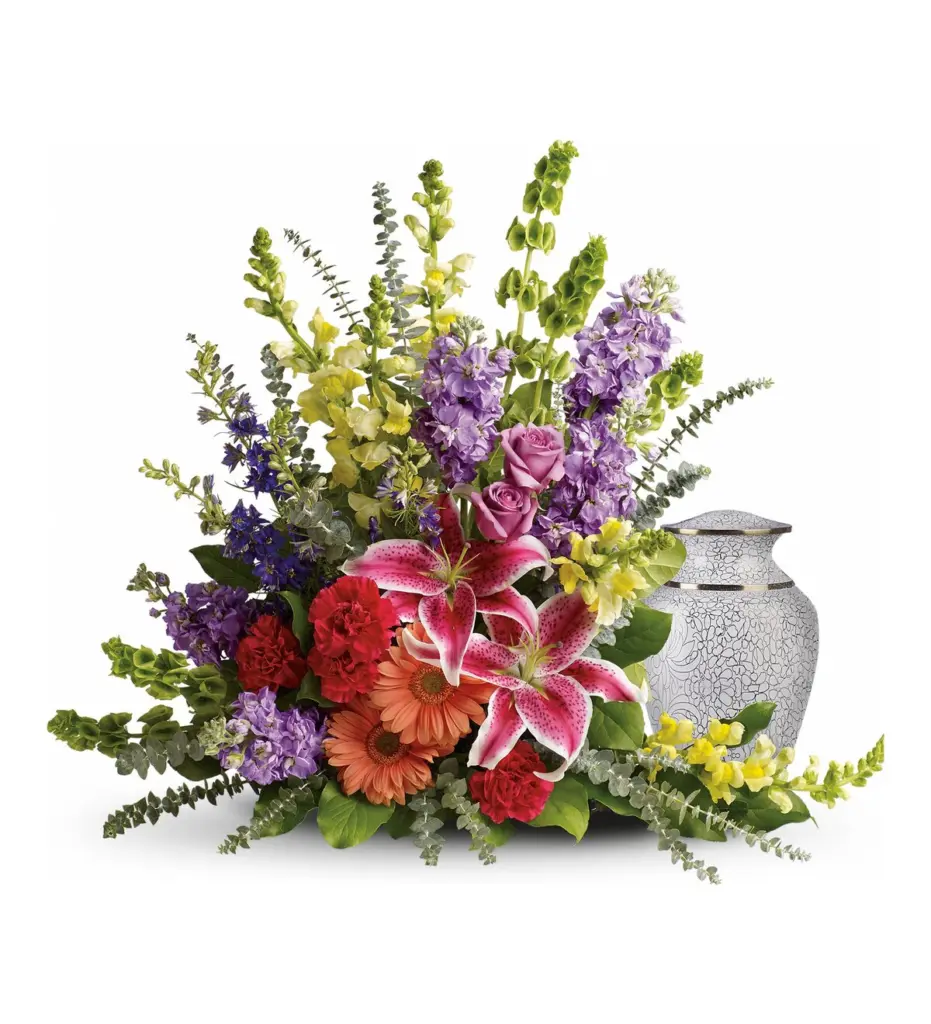 Colorful lilies, snapdragons, stock and gerberas curving around a white patterned urn