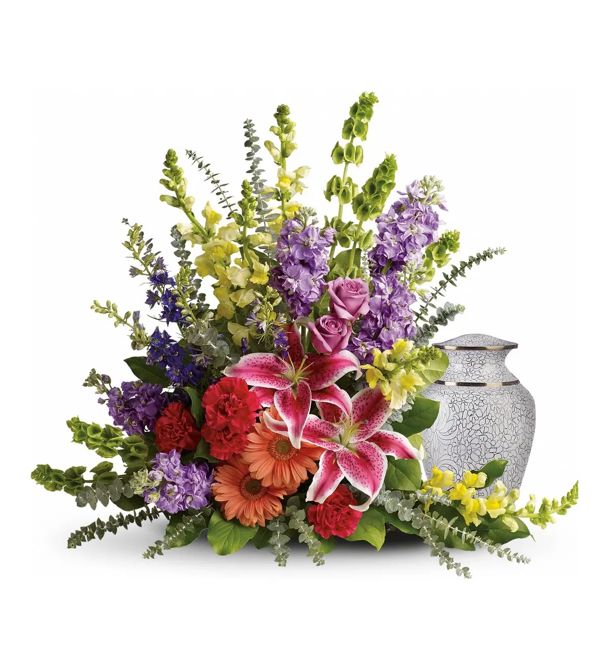 Colorful lilies, snapdragons, stock and gerberas curving around a white patterned urn
