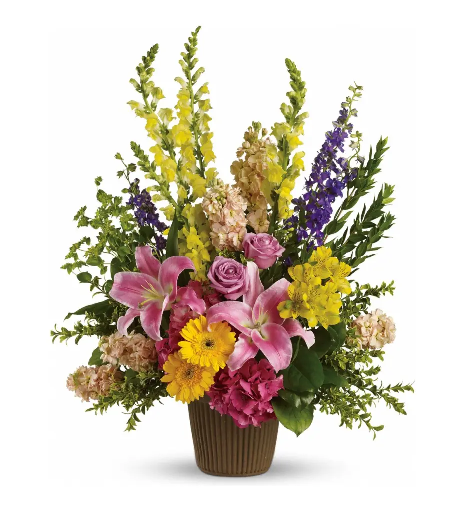 Colorful arrangement of snapdragons, pink lilies and roses in a brown ribbed container