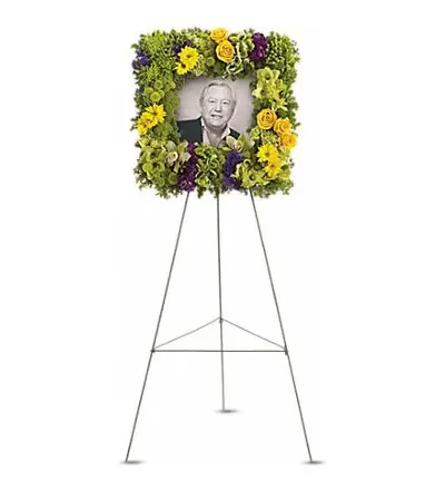 Square flower frame of yellow roses and green orchids around a photo on easel